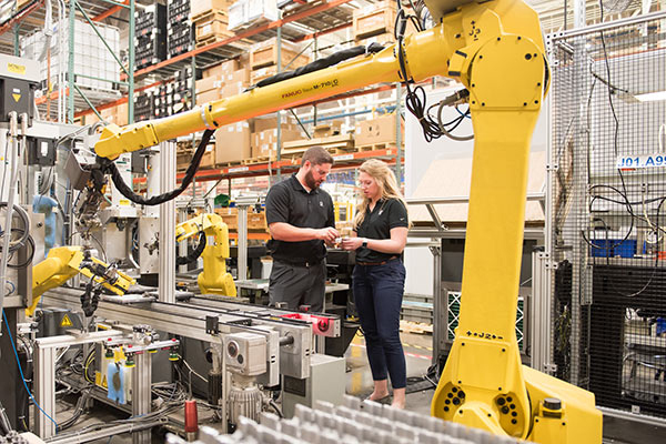 Woman and man in a factory with a robot