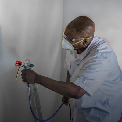 Man painting a wall with a sprayer